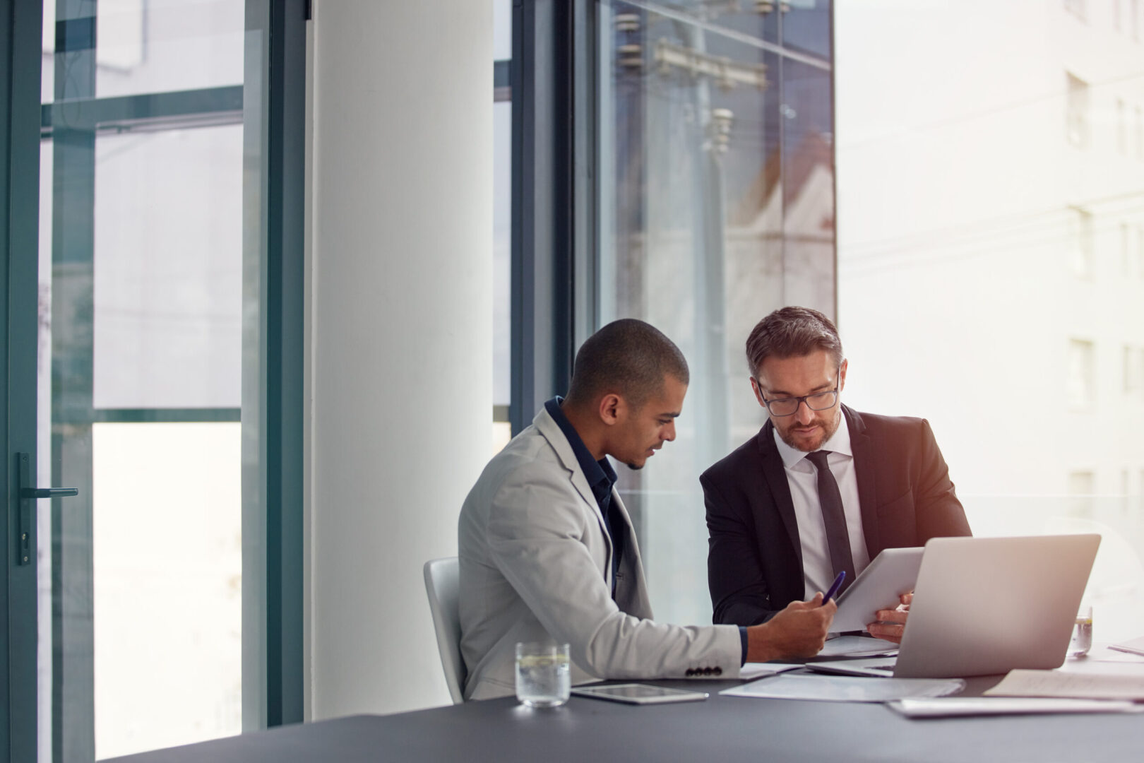 Two colleagues reviewing documents by laptop