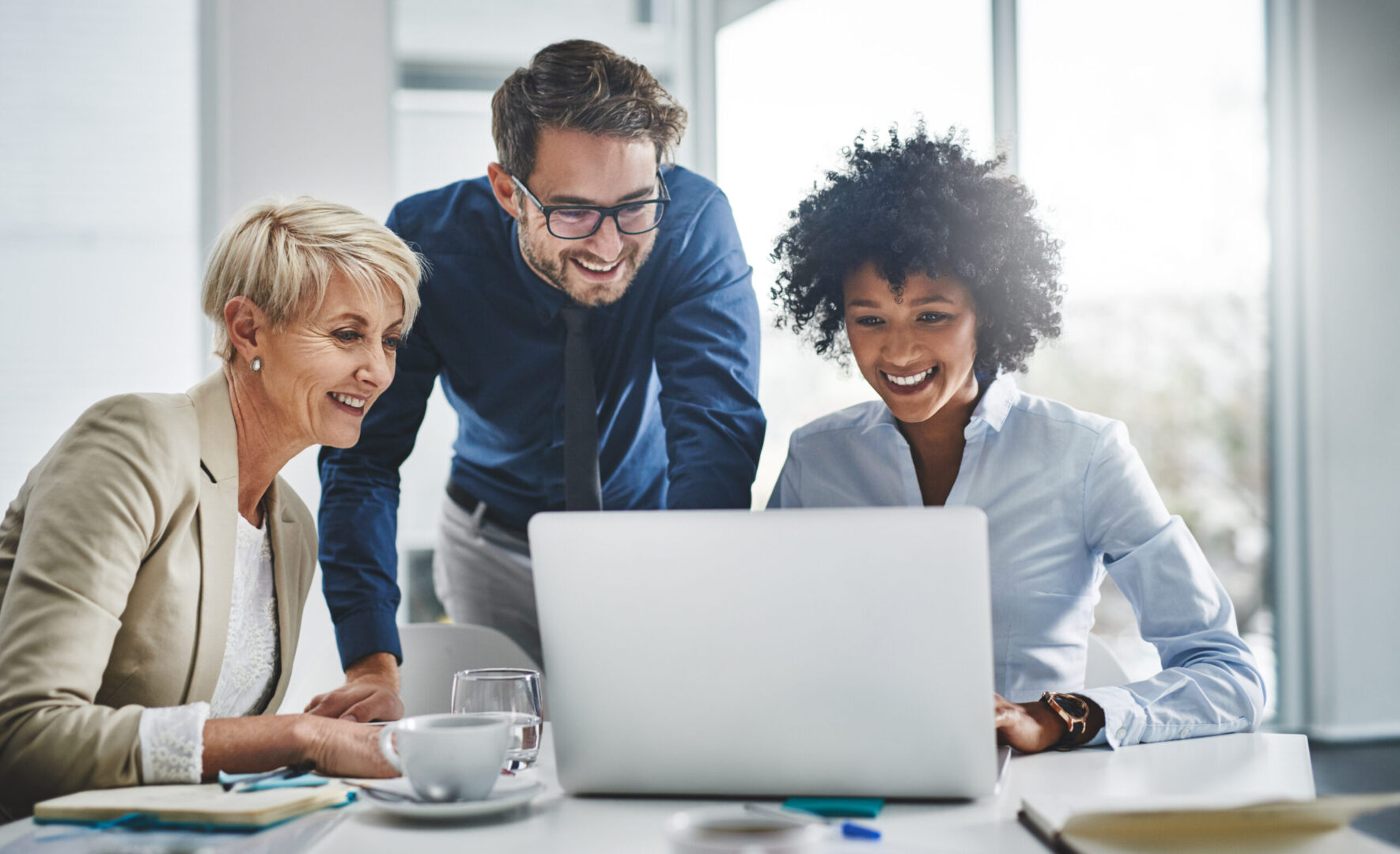 Team smiling while collaborating on a laptop