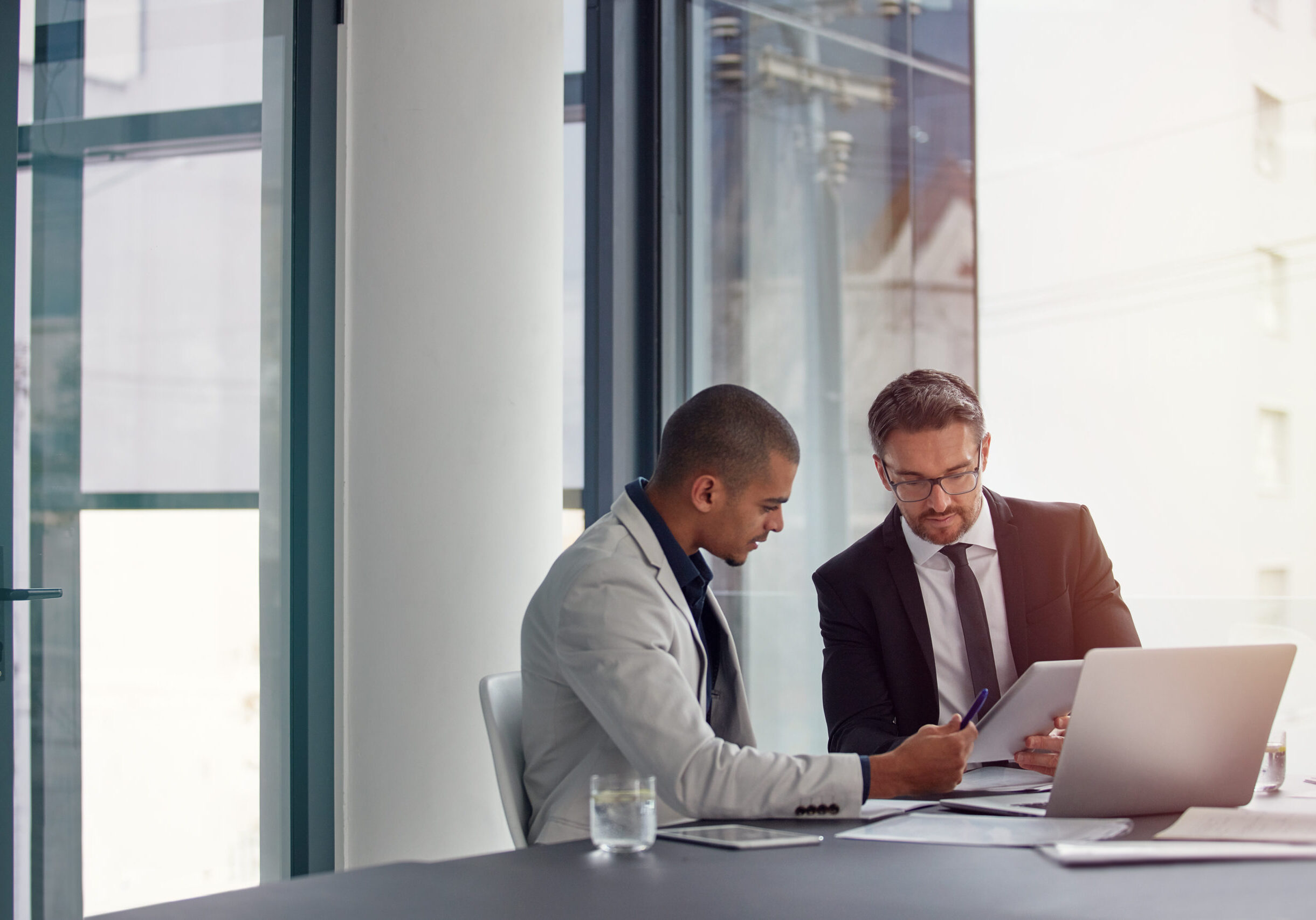 Two colleagues reviewing documents by laptop