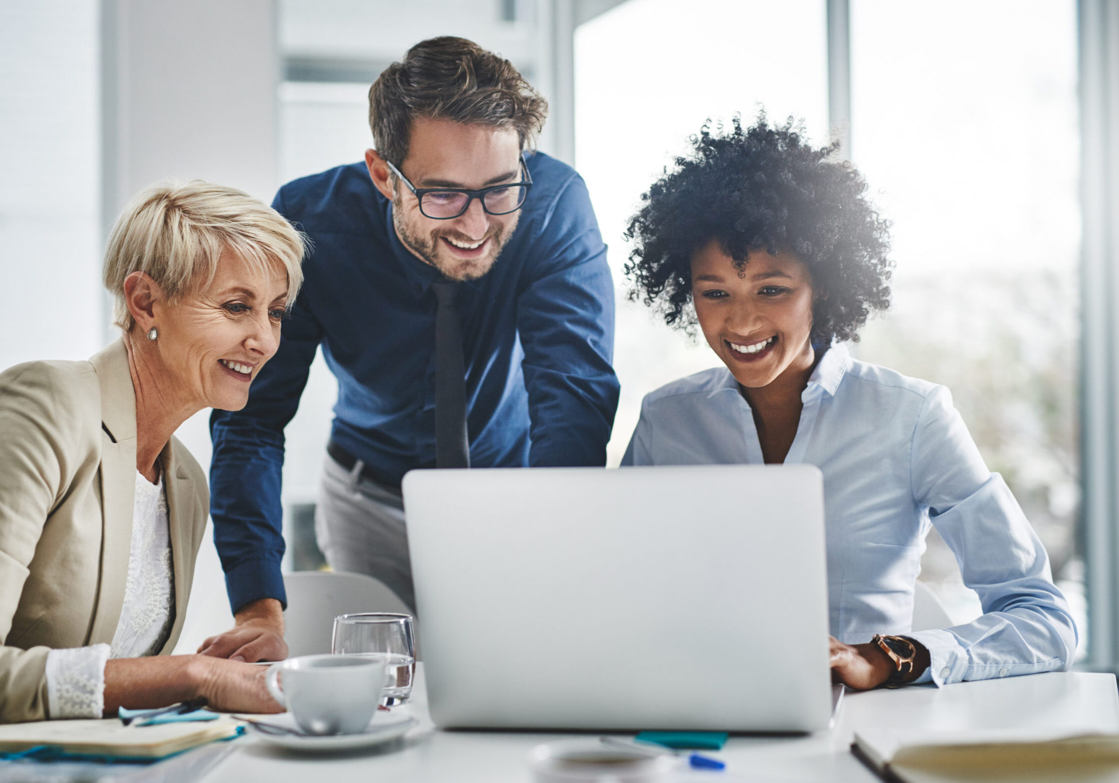Team smiling while collaborating on a laptop